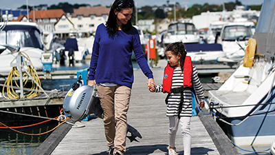 Une femme tenant la main avec sa fille portant une Honda hors-bord